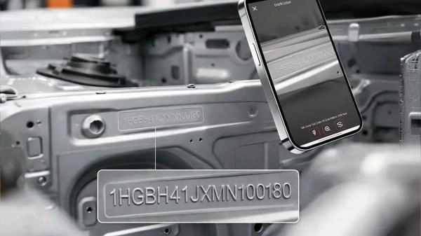 Smartphone using barKoder VIN OCR to read an engraved VIN on a car chassis, with the recognized VIN highlighted in an overlay.