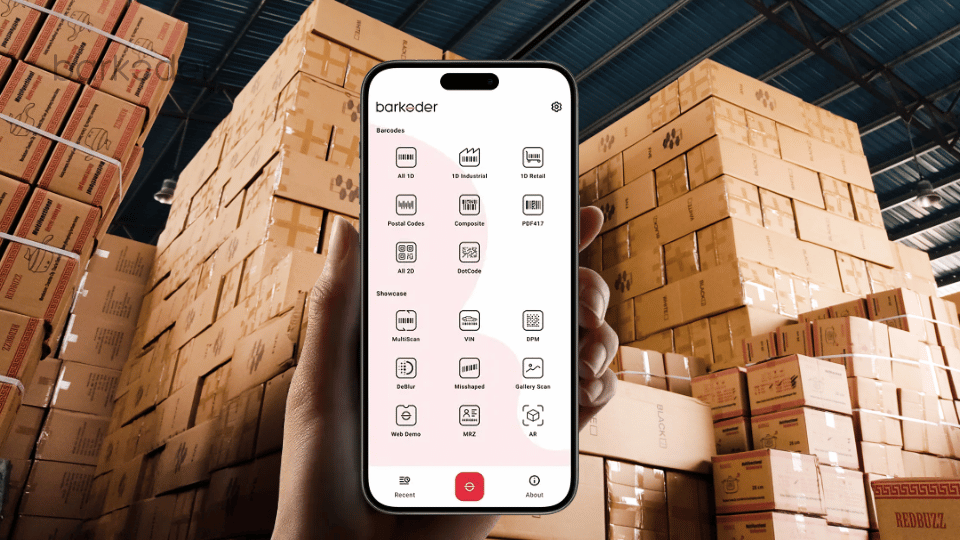 Smartphone showing the barKoder scanning app in front of stacked warehouse boxes.